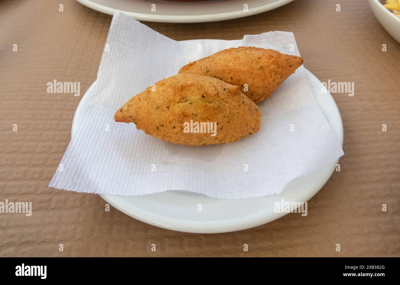 Bolinhos de bacalhau den Teller. Pasteis de bacalhau traditioneller portugiesischer Snack aus einer Mischung aus Kartoffeln, Kabeljau, Eiern, Petersilie und Zwiebeln. Stockfoto