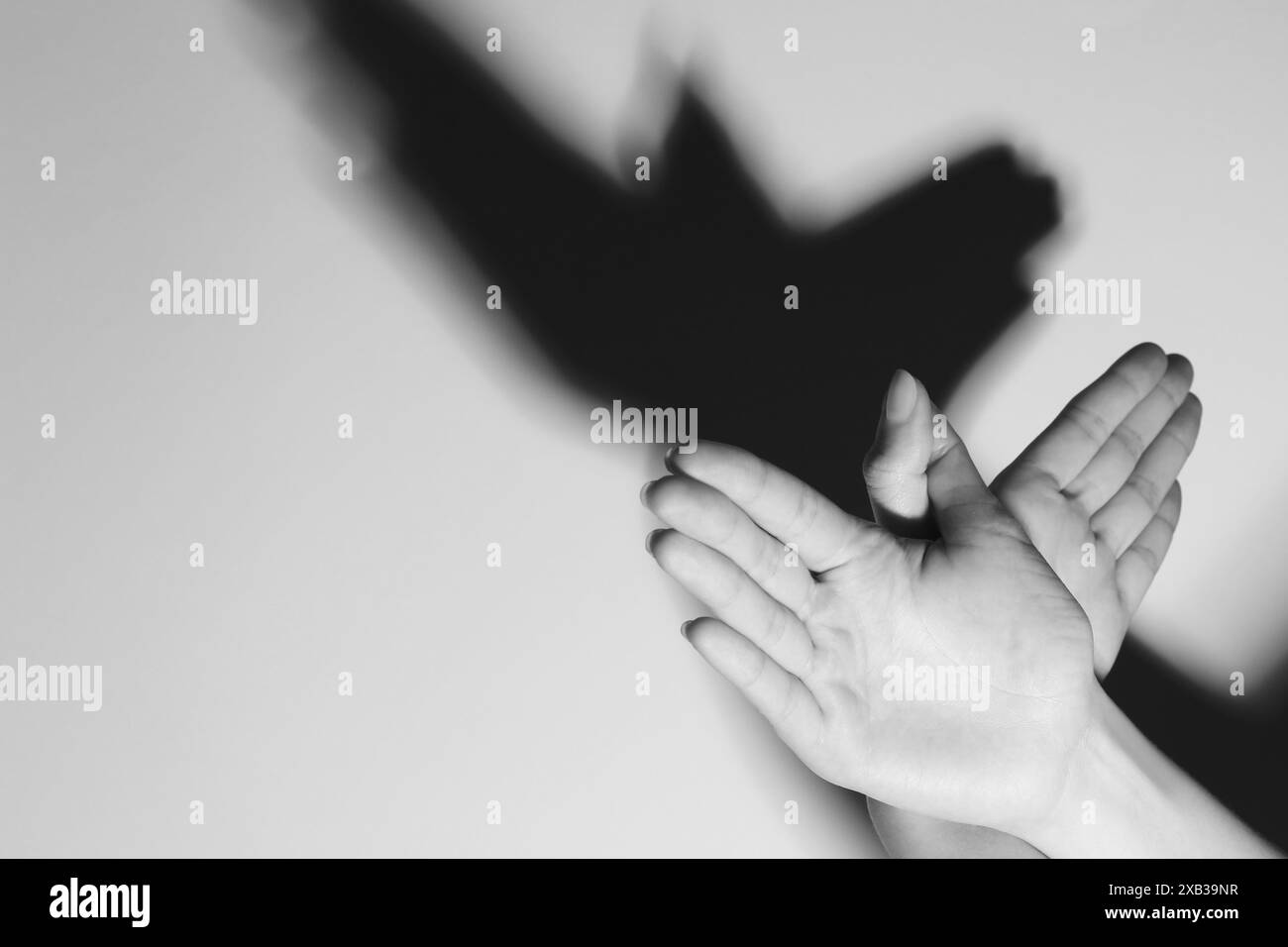 Frau macht Handgeste wie Vogel auf hellem Hintergrund, Nahaufnahme mit Platz für Text. Schwarzweiß-Effekt Stockfoto