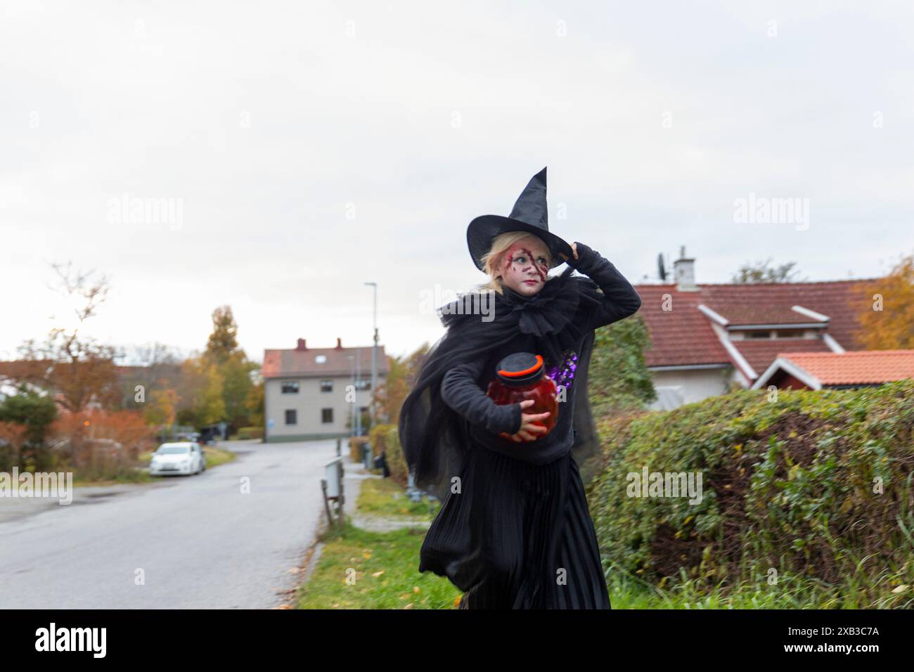 Ein Mädchen trägt Hexenkostüm und läuft an Halloween auf der Straße in der Stadt Stockfoto