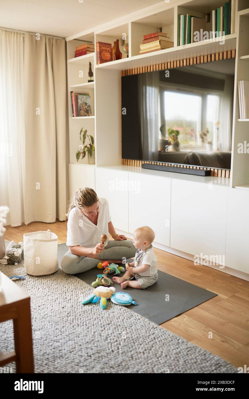 Mutter und Sohn spielen zu Hause mit Spielzeug auf dem Teppich Stockfoto