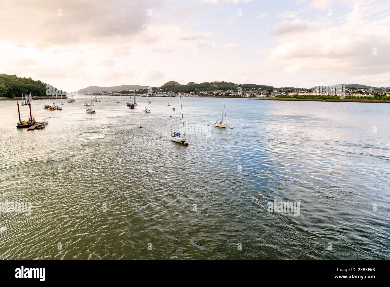 Salingboote legen bei Sonnenuntergang im Sommer an Bojen im Hafen von Conwy fest Stockfoto