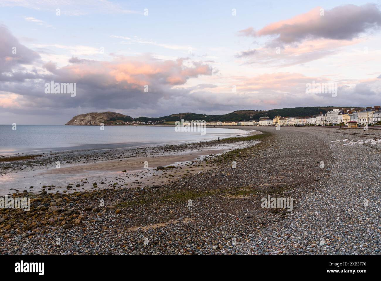 Blick auf einen Kiesstrand, gesäumt von einer Promenade und pastellfarbenen viktorianischen Gebäuden in einem Badeort in der Abenddämmerung im Sommer Stockfoto