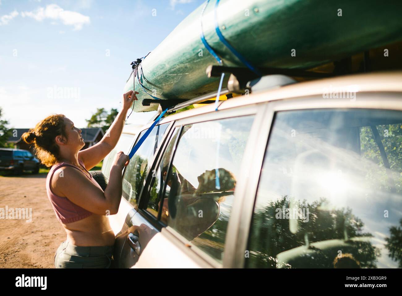 Frau, die am sonnigen Tag am Wochenende Kajak auf die Motorhaube legt Stockfoto