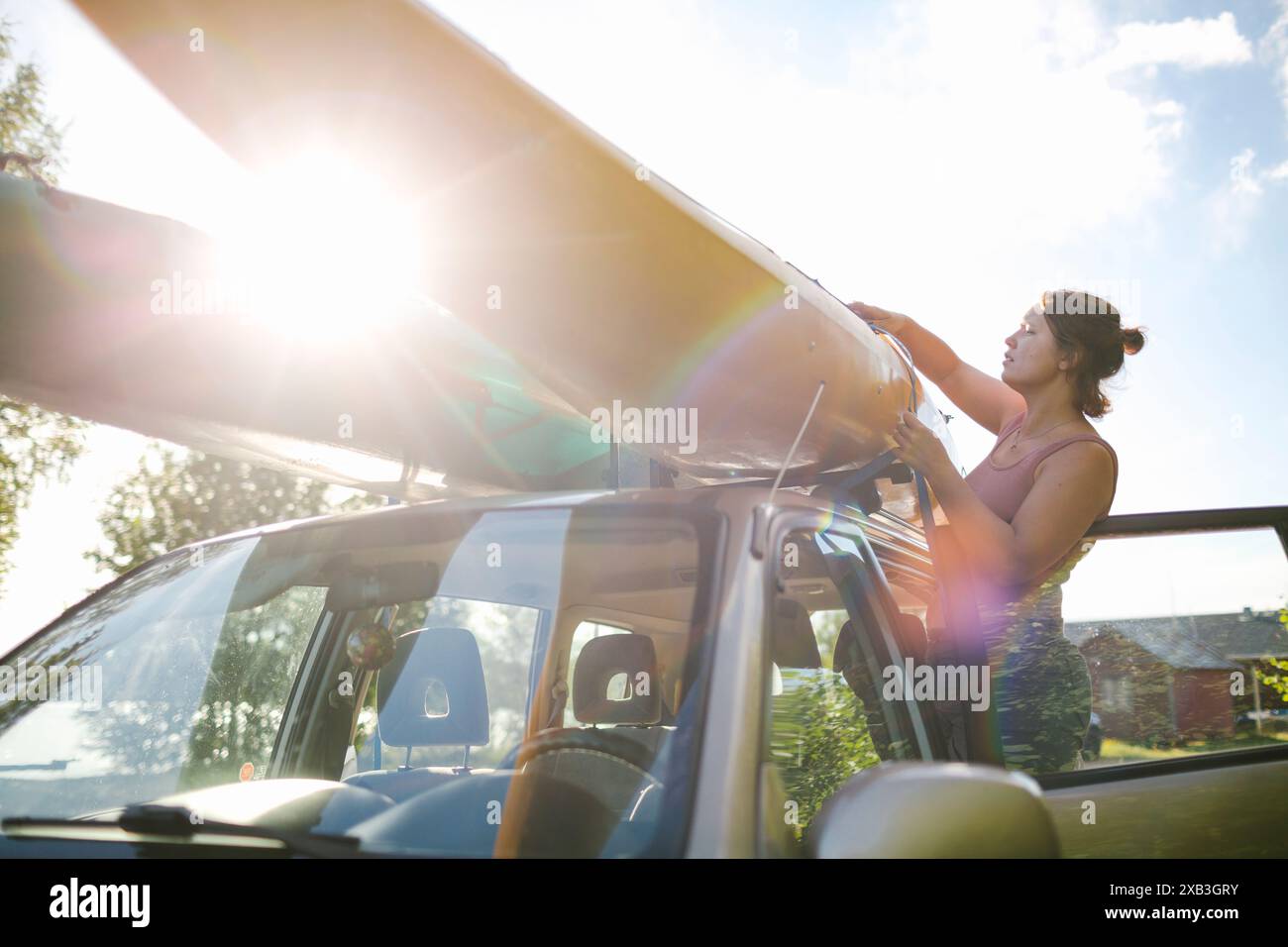 Frau, die am Wochenende am sonnigen Tag Kajak auf die Motorhaube legt Stockfoto