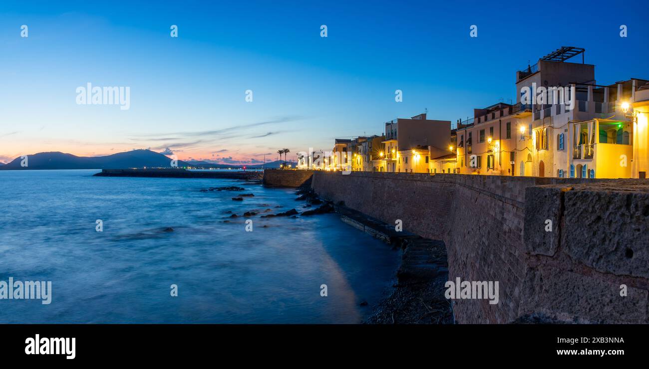Blick auf die ummauerte Stadt und die Stadtmauern von Alghero bei Nacht, Insel Sardinien, Italien Stockfoto