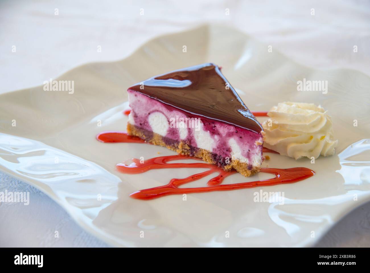 Nachtisch: Käsekuchen mit Himbeermarmelade und Erdbeersirup. Ansicht schließen. Stockfoto