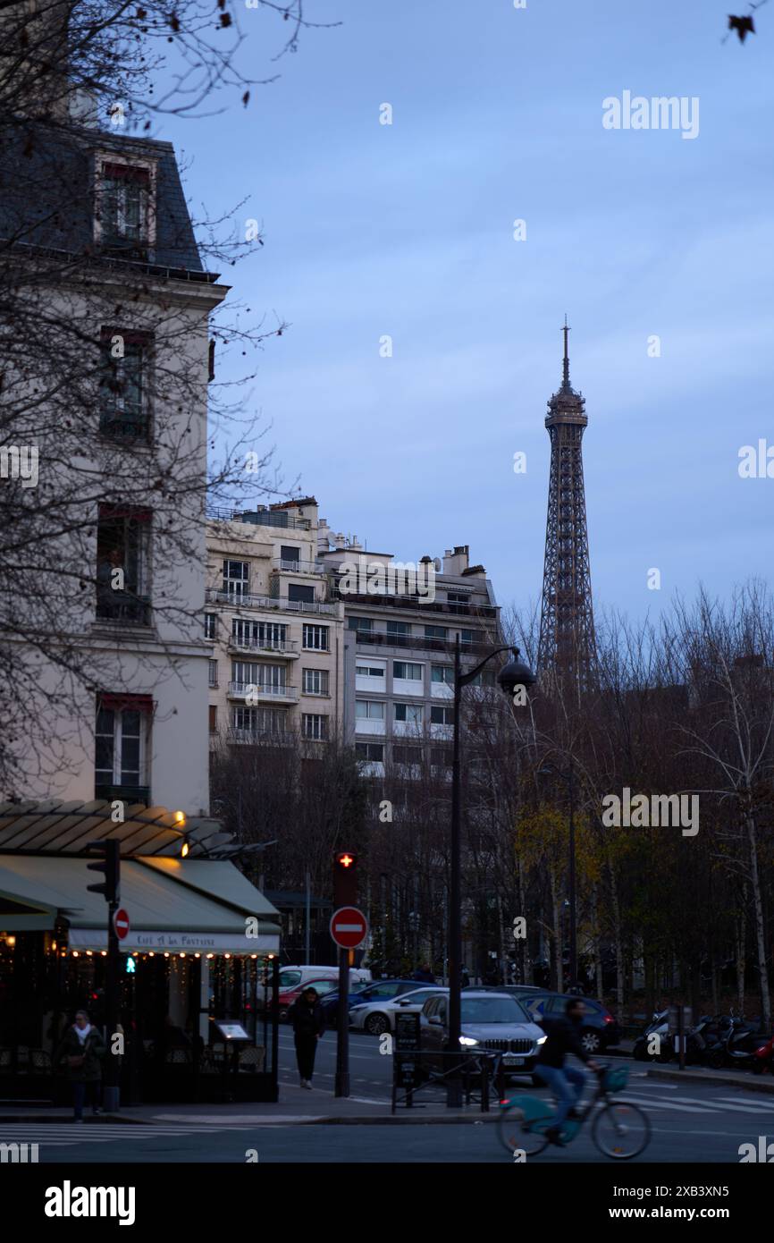 Ein Blick auf die Eiffeltour in Paris vom 16. Arrondissement aus, an dem ein Radfahrer im Vordergrund vorbeireitet Stockfoto