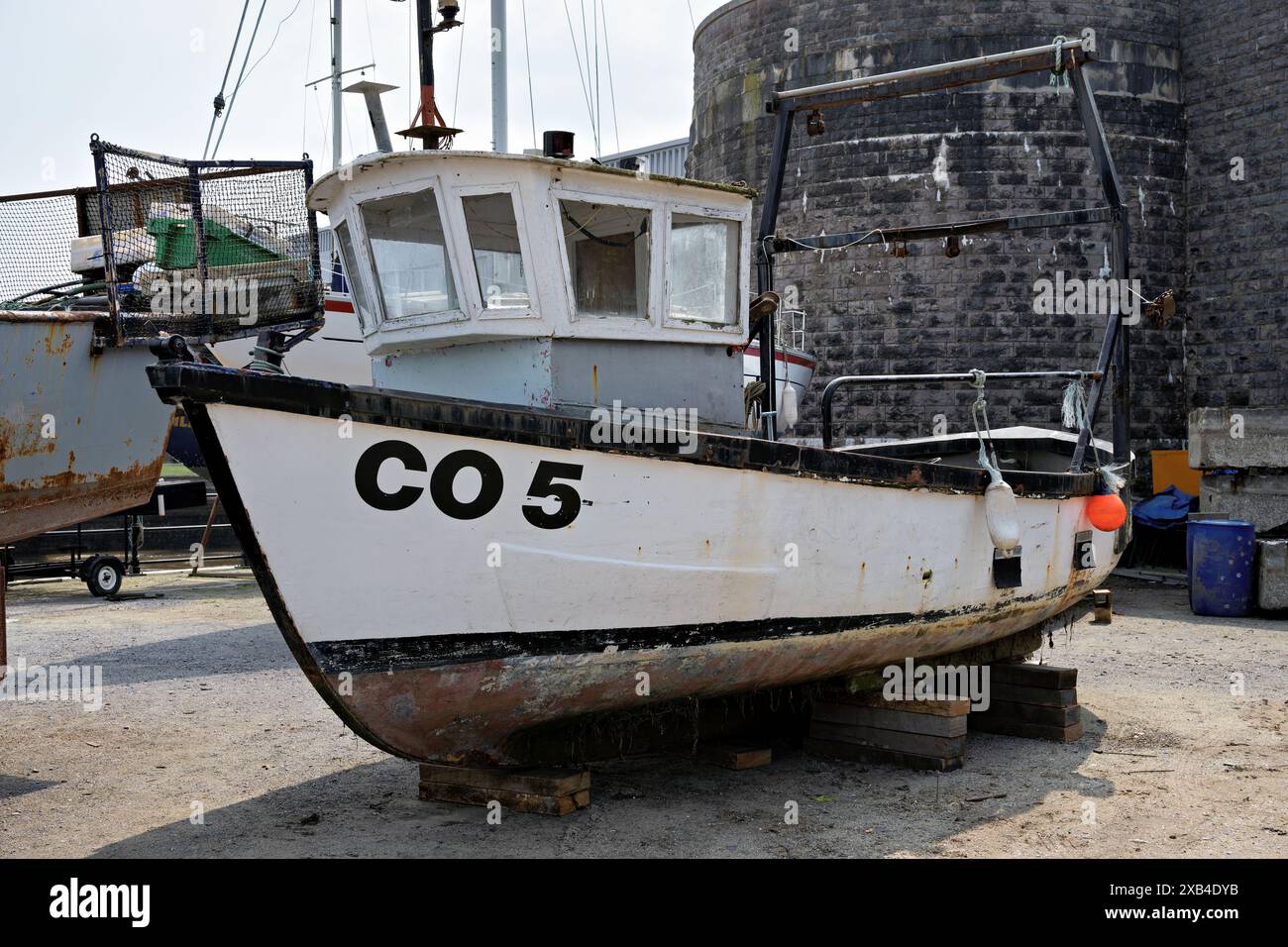 Conwy Wales UK 06-01-2024. Altes Fischerboot 'CO 5', das auf Holzblöcken durch eine Steinmauer angedockt ist und in der Nähe eine Schiffsausrüstung hat Stockfoto