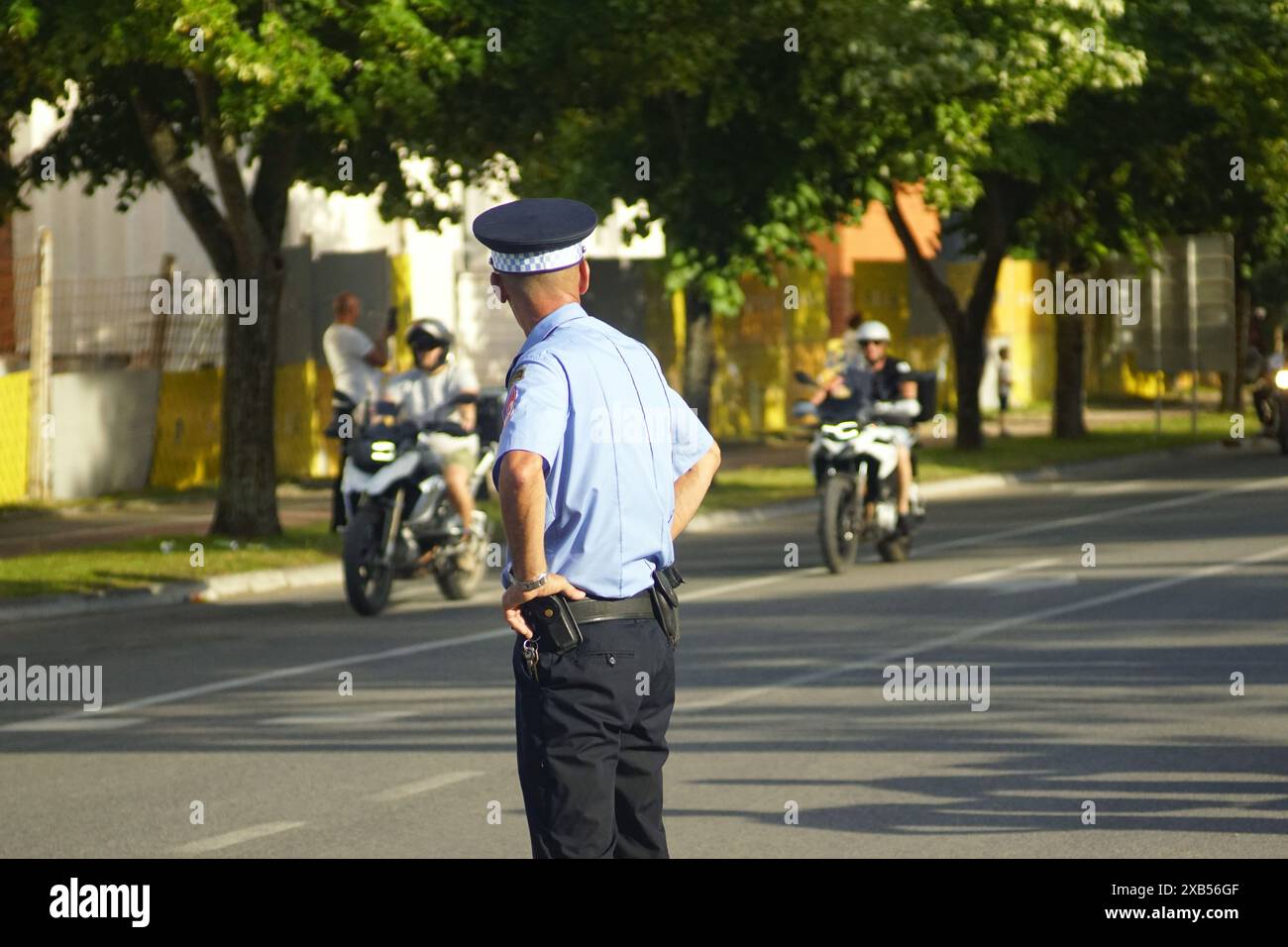 Ein Polizist hält Ordnung beim 24. Motorradtreffen. Ein Streifenpolizist, der auf der Straße steht, beobachtet Motorradfahrer, die an einer Stadtstraße vorbeifahren. Stockfoto