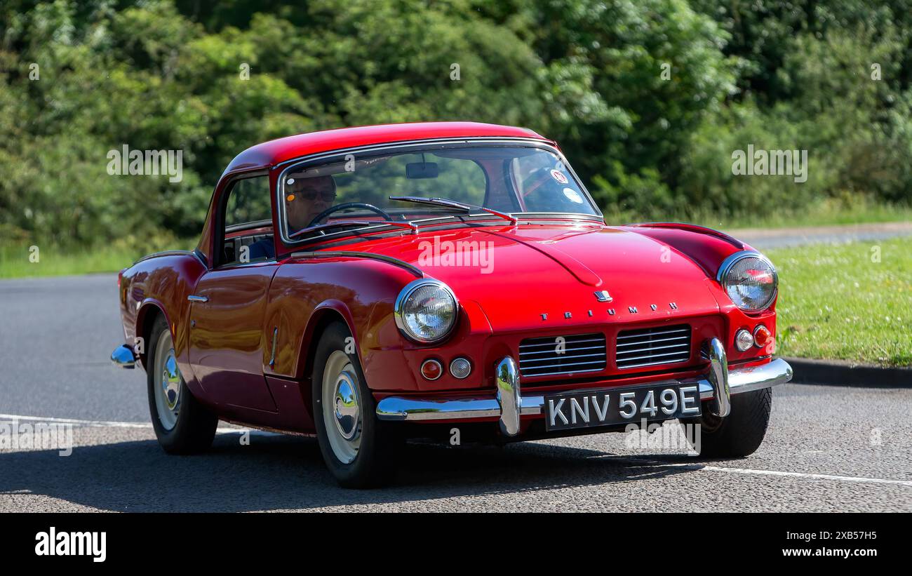 Stony Stratford, UK - 2. Juni 2024: 1967 roter Triumph Spitfire klassischer britischer Sportwagen, der auf einer britischen Landstraße fährt Stockfoto