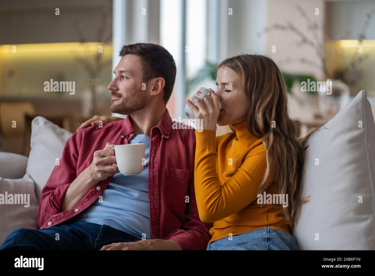 Morgens Kaffeepause liebevolles Paar zu Hause sitzt auf der Couch ruhig und träumt zusammen, schaut ins Fenster. Stockfoto