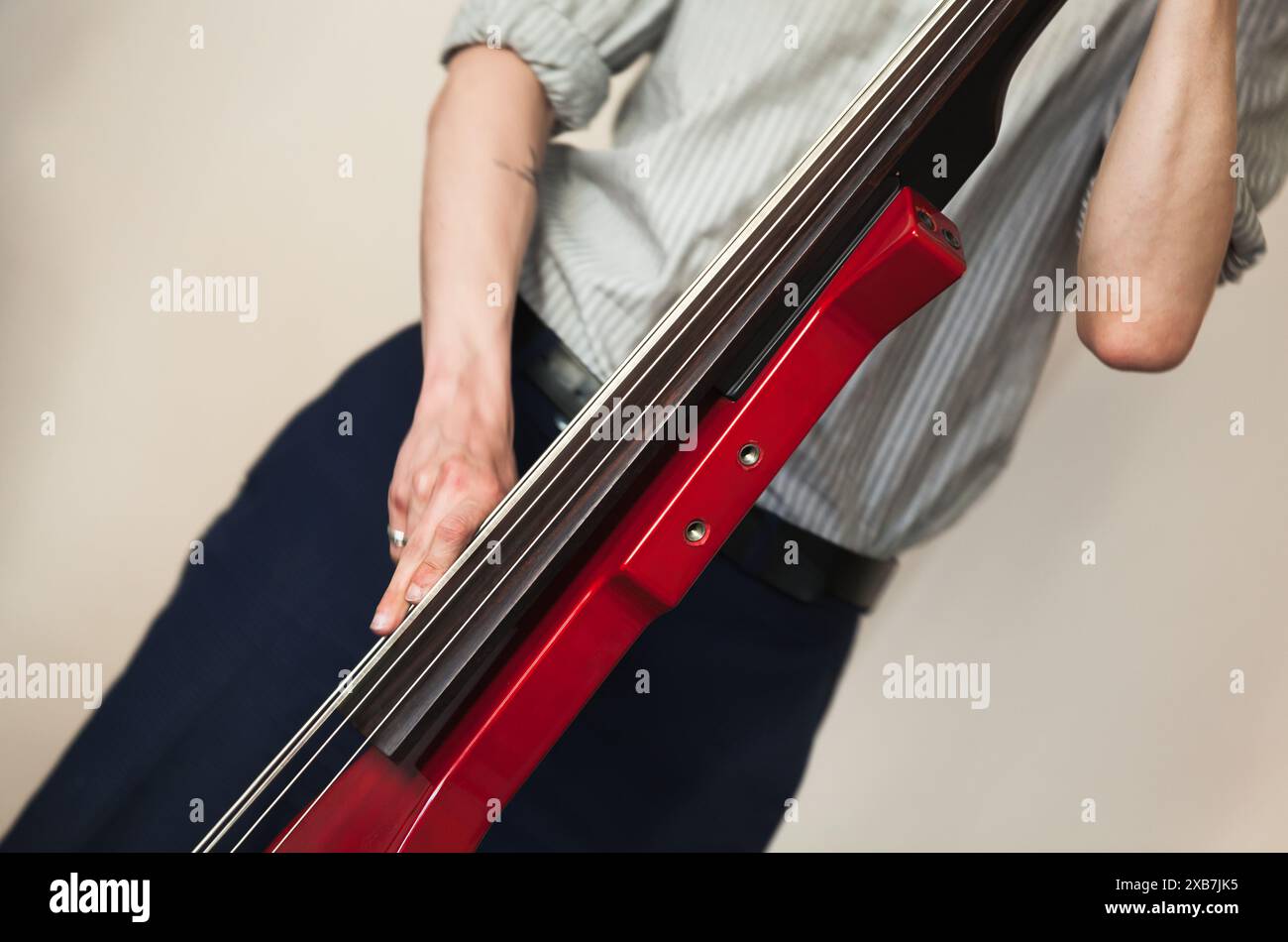Ein Mann, der roten elektrischen Kontrabass spielt. Nahaufnahme mit selektivem Fokus. Live-Musik-Foto-Hintergrund Stockfoto