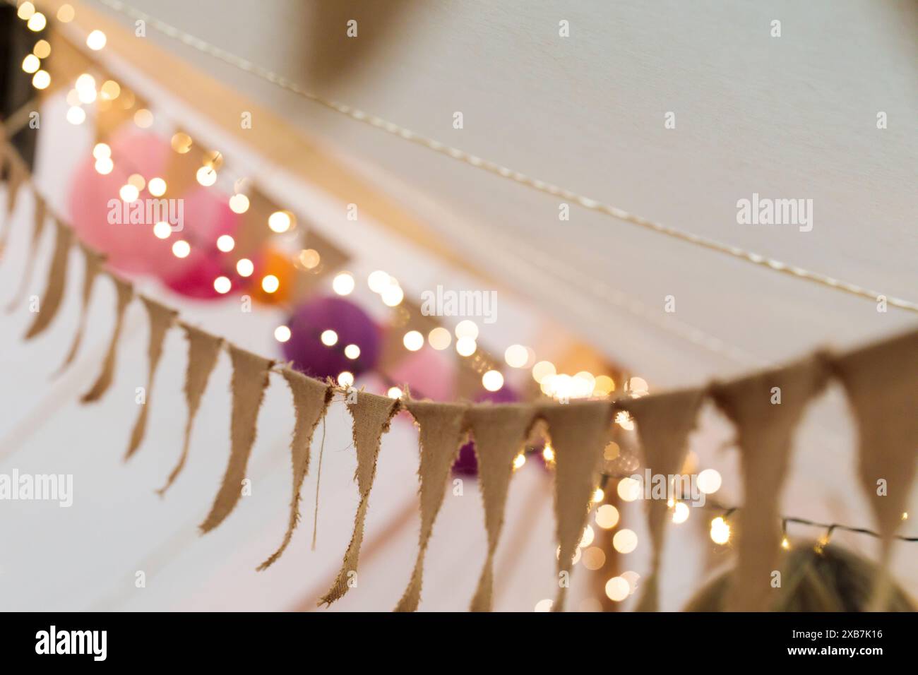 Ein natürlicher hessischer Faden, der sich um das Innere eines Zeltes für eine Hochzeit oder ein fest mit Feenlichtern im Hintergrund herumhängt. Stockfoto