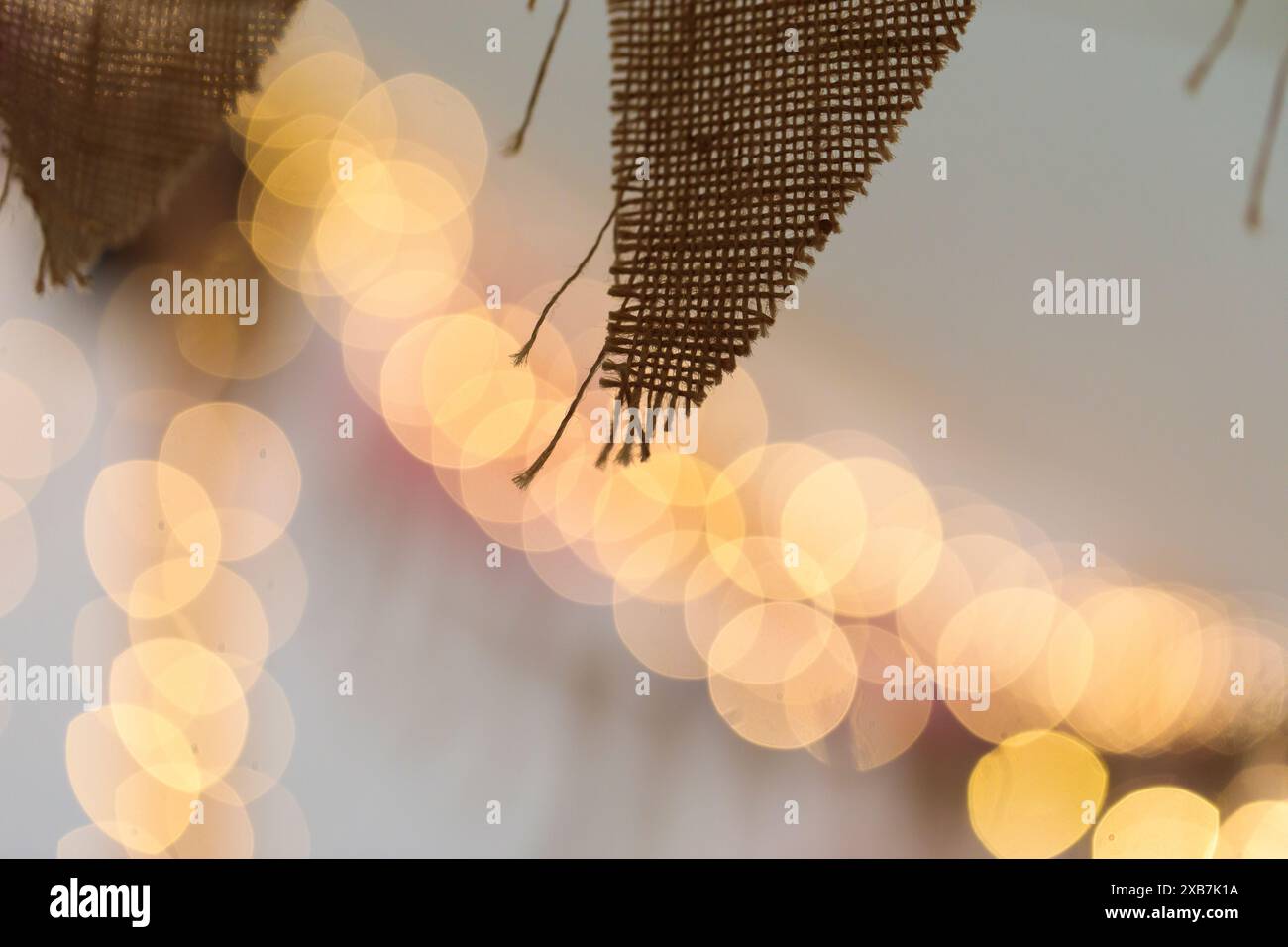 Ein natürlicher hessischer Faden, der sich um das Innere eines Zeltes für eine Hochzeit oder ein fest mit Feenlichtern im Hintergrund herumhängt. Stockfoto