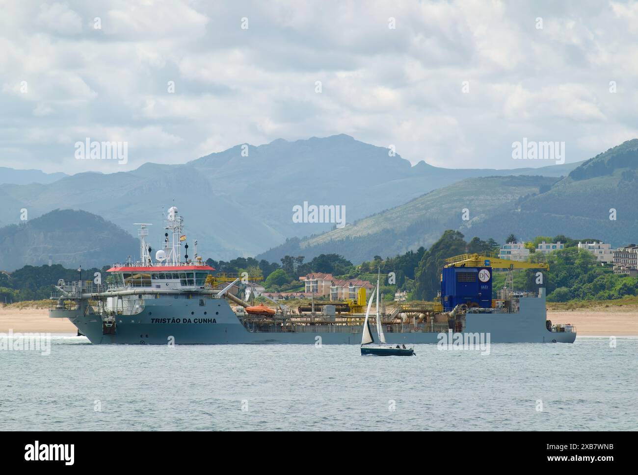 Eine Yacht, die an dem Hopper-Bagger-Schiff Tristao da Cunha vorbeifährt und in der Bucht Santander Cantabria in Spanien arbeitet Stockfoto