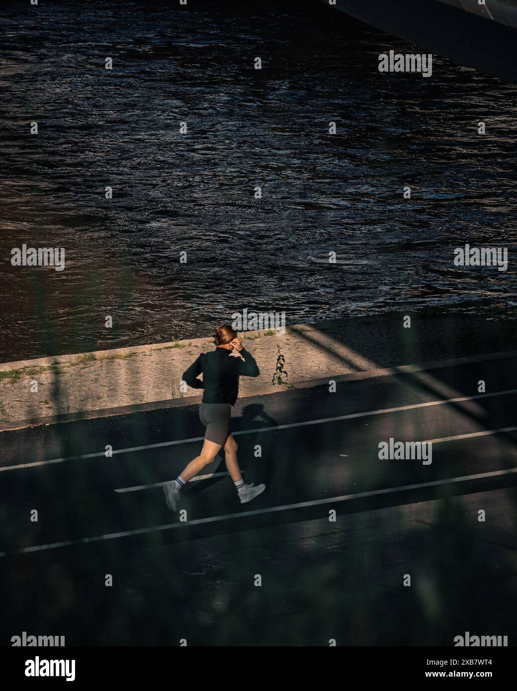 Eine Frau, die in der Abenddämmerung am Wasser joggt Stockfoto