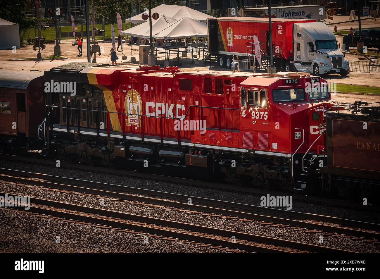 Eine rote Lokomotive mit Eiswagen und anderen Autos, auf einer Bahnstrecke Stockfoto