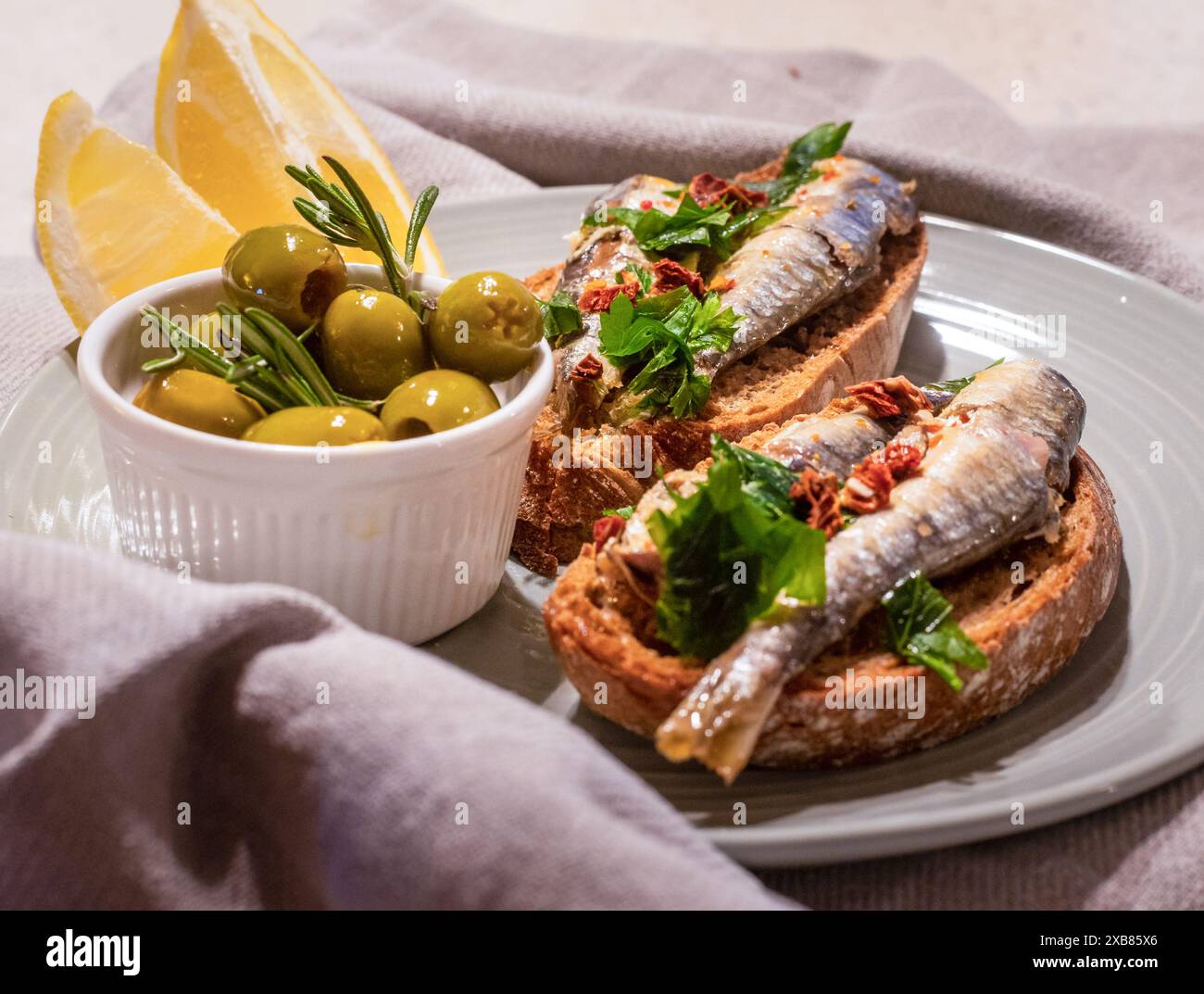 Teller mit Fisch, Oliven, Brot und Zitronenscheibe Stockfoto