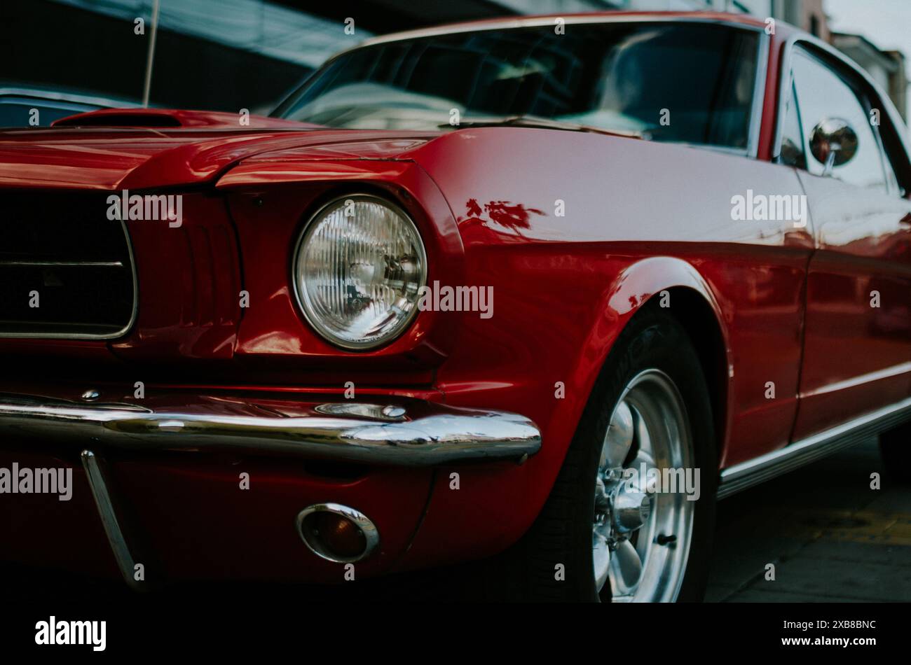 Roter Vintage Mustang parkte neben einem anderen Fahrzeug in der Stadt Stockfoto