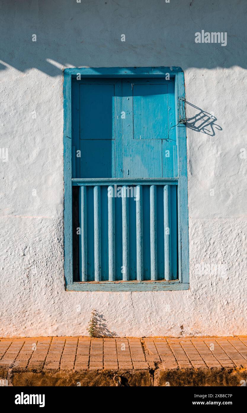 Weiße Stuckwand mit blauem Fenster und Holztür Stockfoto