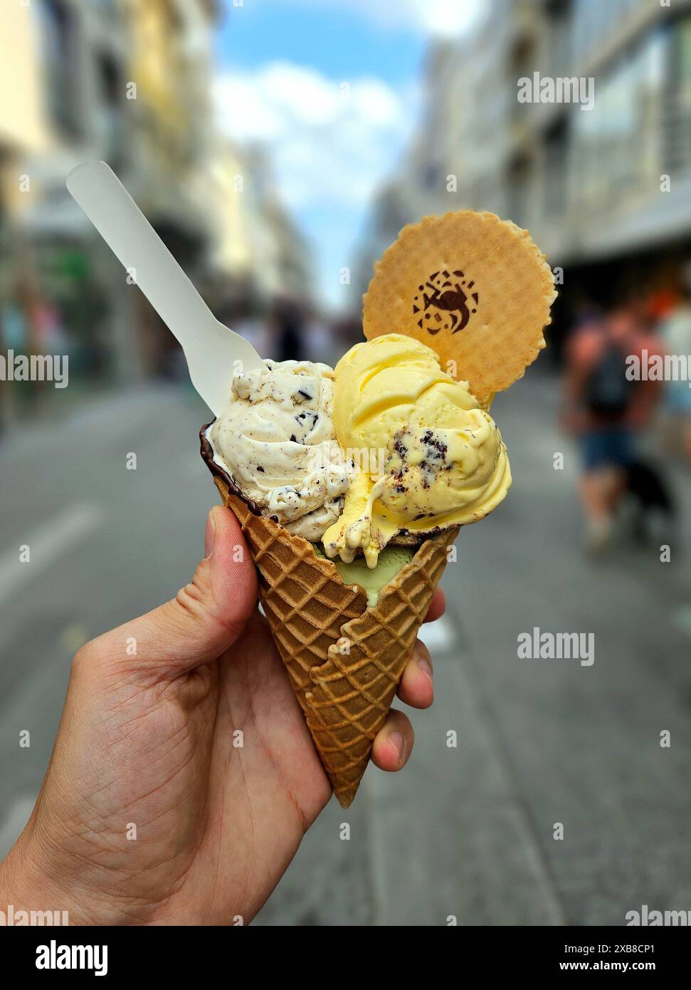 Eine Hand, die eine Eiskegel mit zwei Kugeln Eis hält Stockfoto