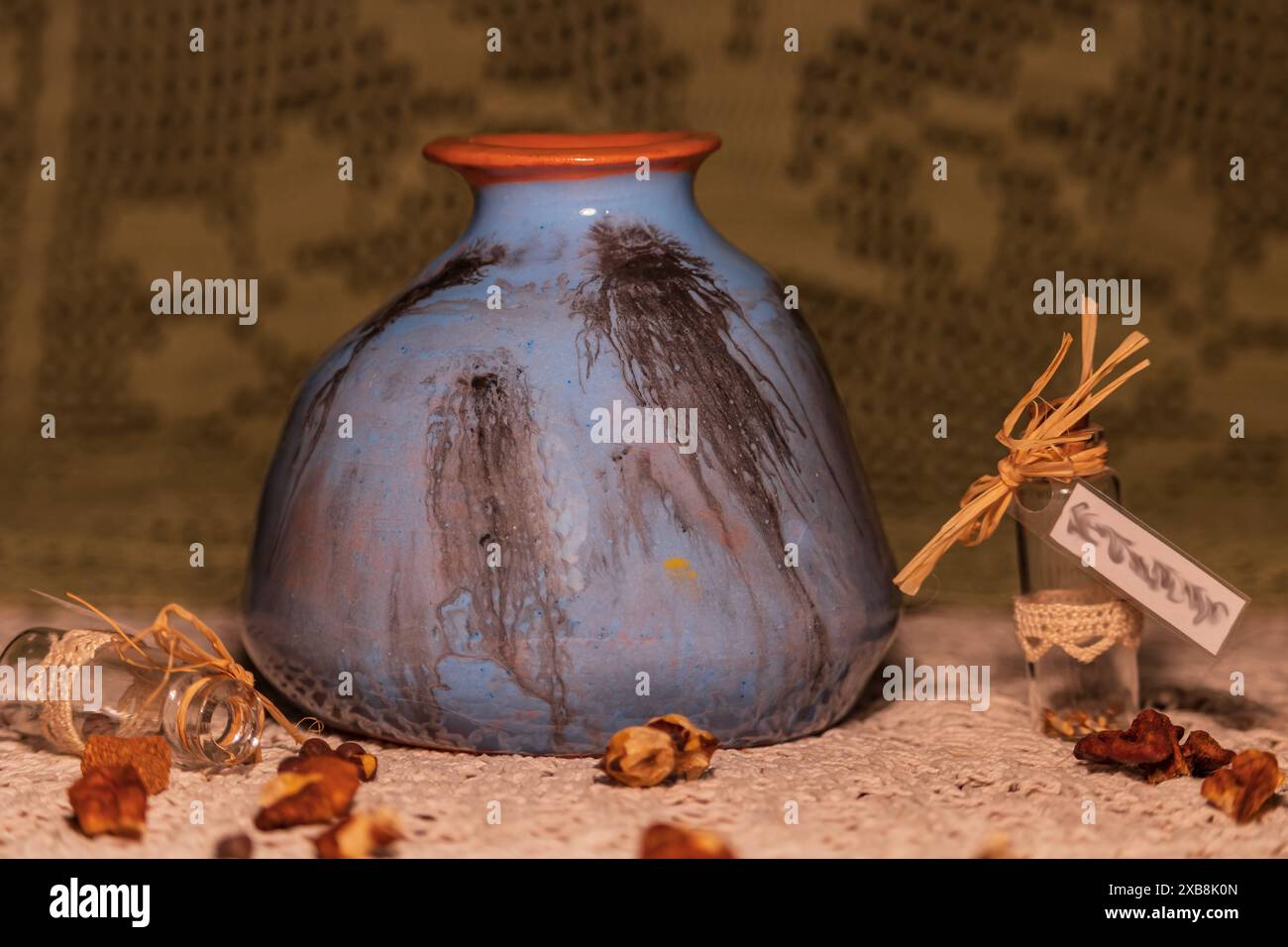 Rustikale handgefertigte Keramikvase mit getrockneten Kräutern und Glasflaschen Stockfoto