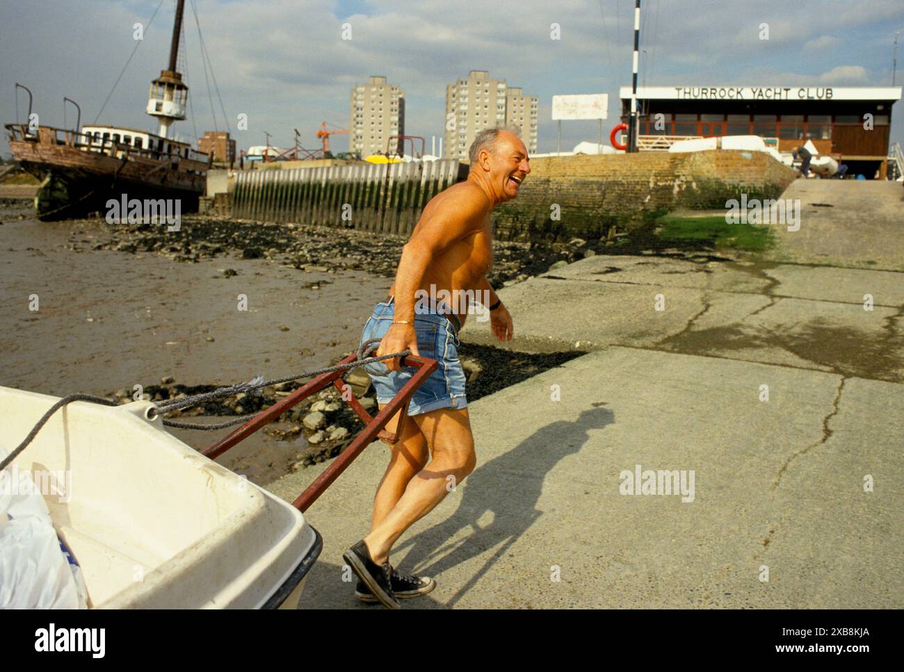 Essex Mann mittleren Alters lacht und schleppt ein kleines Boot an Land in die Hangbahn im Thurrock Segelclub, England 1991 1990s UK HOMER SYKES Stockfoto