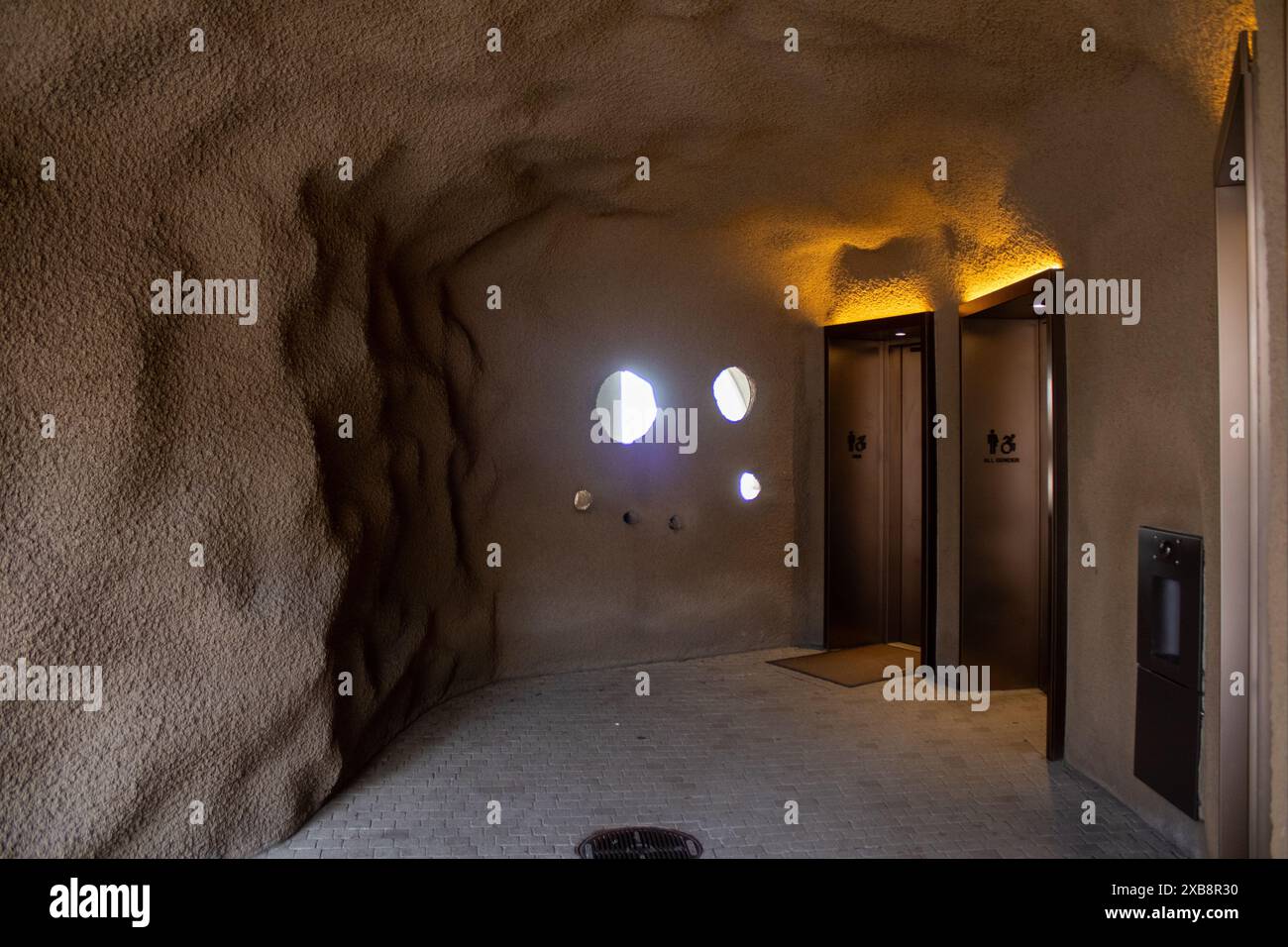 Mehrere Löcher an einer Wand mit zwei modernen Aufzügen daneben in einem alten Gebäude Stockfoto