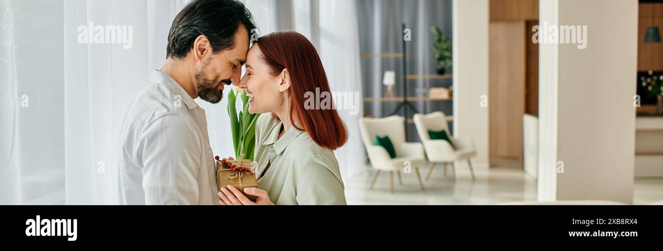 Eine rothaarige Frau und ein bärtiger Mann teilen sich einen zarten Kuss in einem modernen Wohnzimmer, das von modernem Dekor umgeben ist. Stockfoto