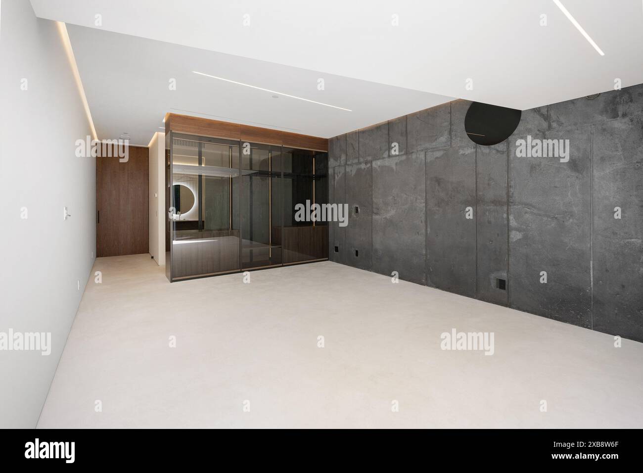 Ein leeres Schlafzimmer mit Betonwänden und einem Deckenventilator Stockfoto