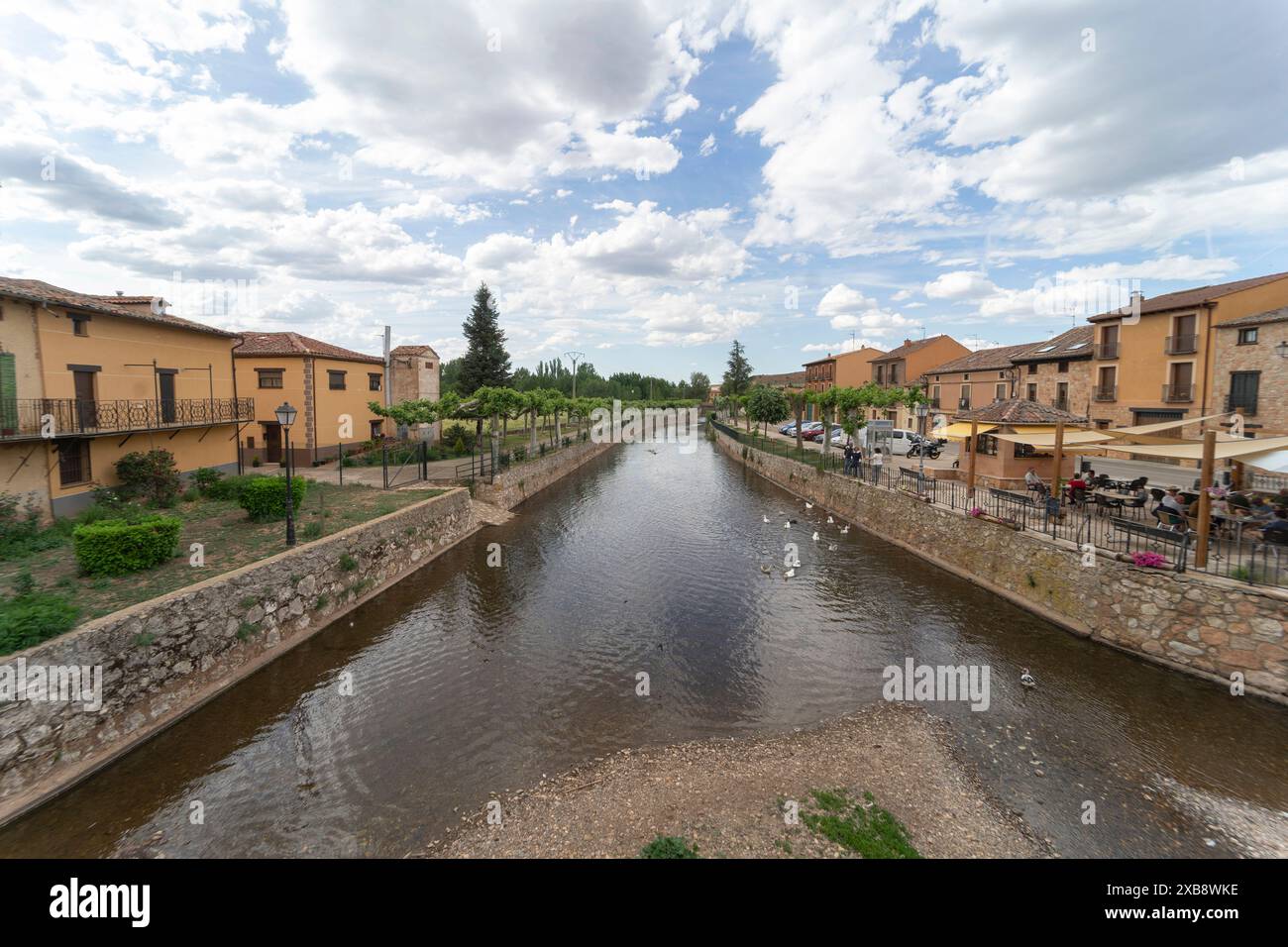 Panoramablick auf das Dorf Ayllon und den Fluss Aguisejo mit einigen Enten, die an einem heißen Sommertag schwimmen. Stockfoto