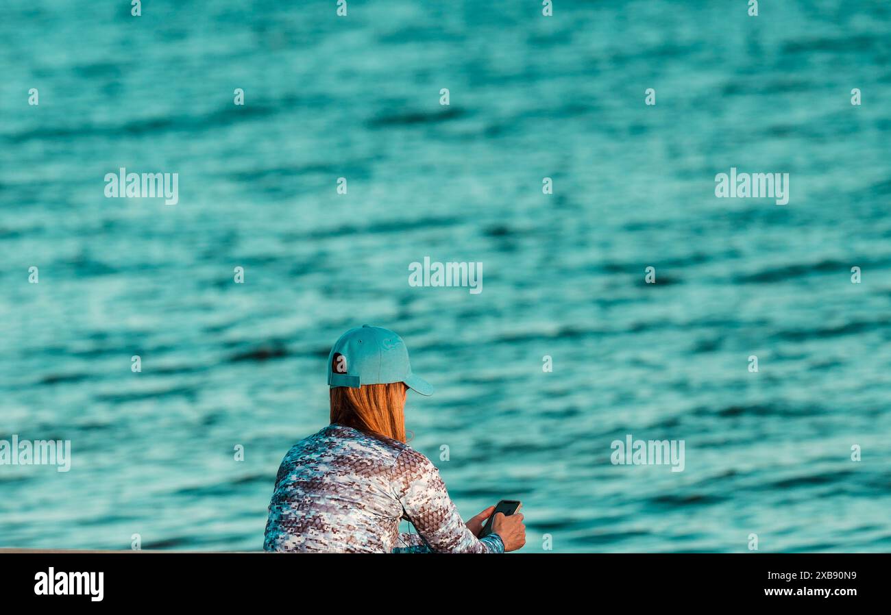 Eine Frau mit blauem Hut am Meer Stockfoto