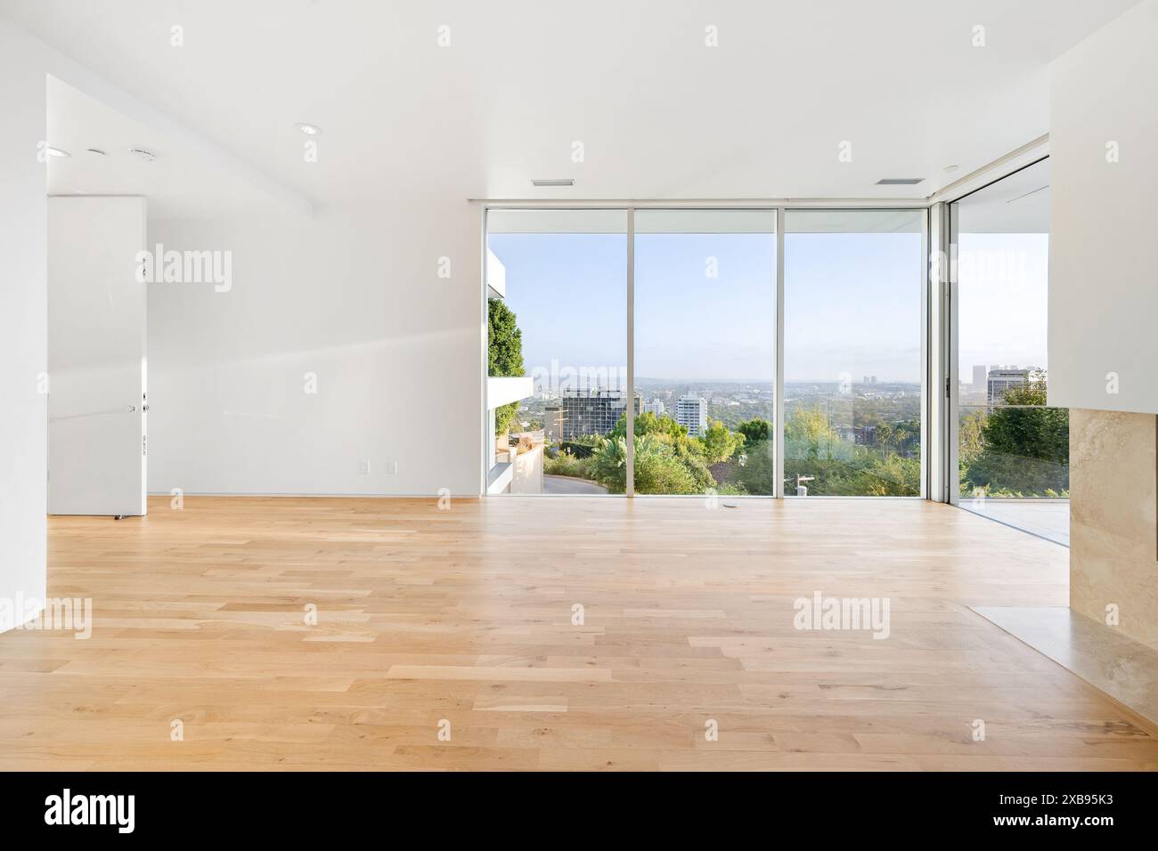 Ein modernes Wohnzimmer mit Hartholzfußboden und großem Fenster mit Blick auf den Baum Stockfoto