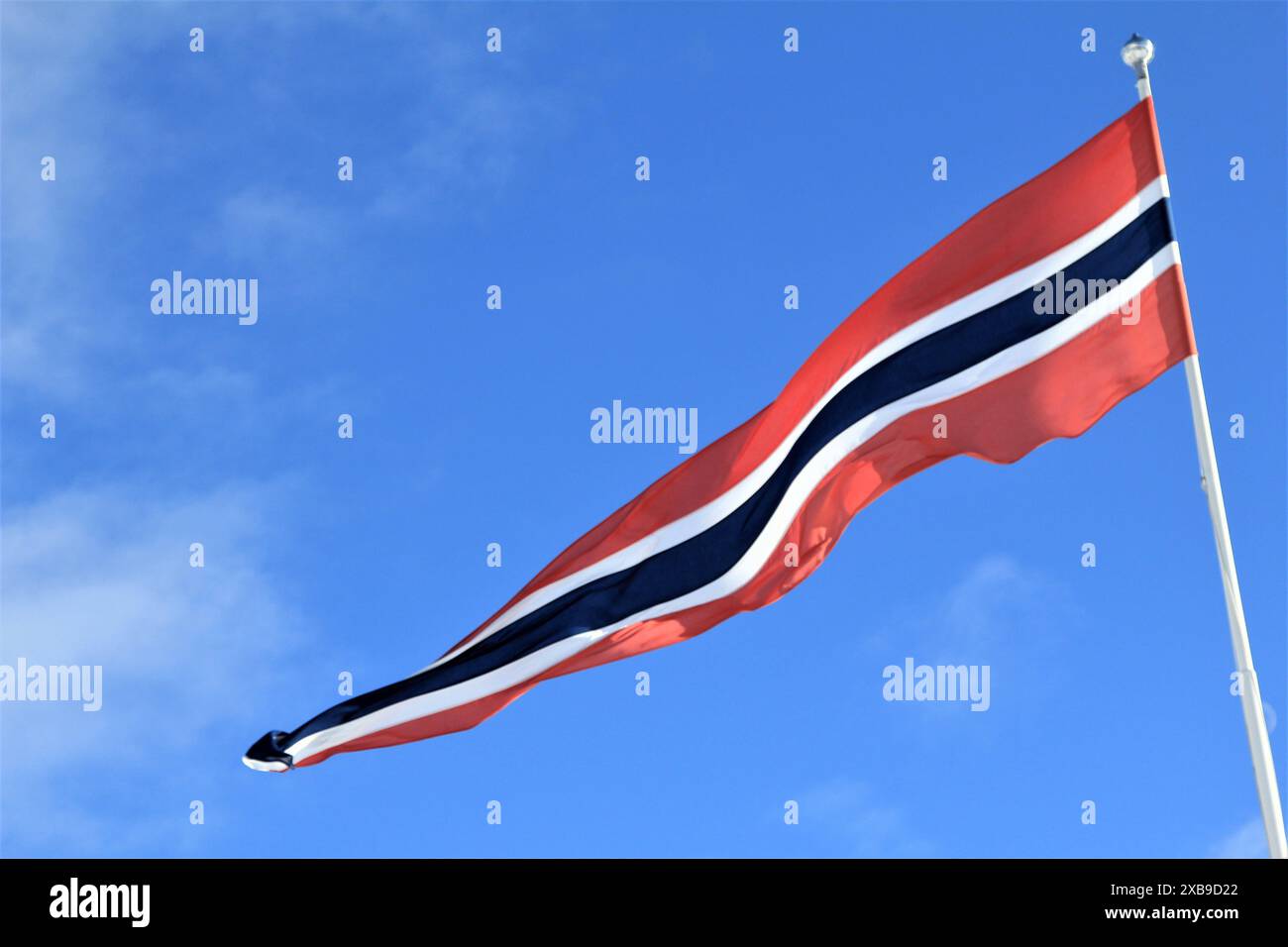 Die Flagge Norwegens flattert im Wind unter blauem Himmel Stockfoto