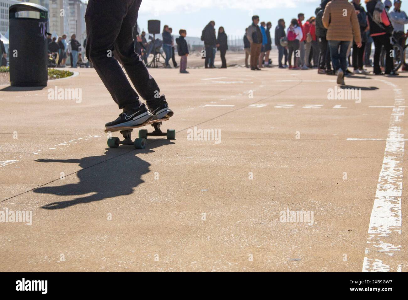 Skateboard mit Nike Sneakers auf einem Radweg an der Costa Caparica Promenade in Portugal Stockfoto