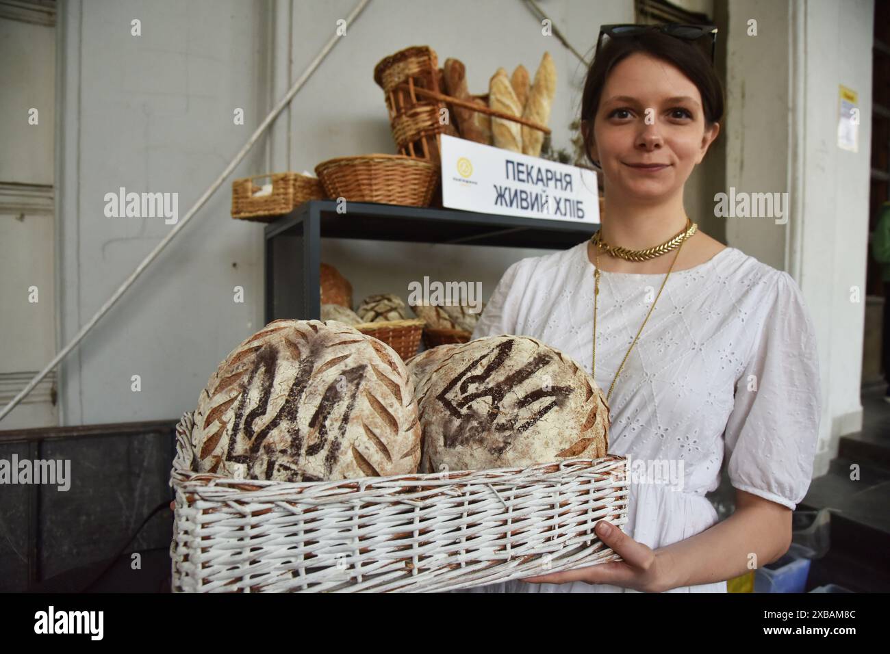 Ein Mädchen hält einen Korb mit Brot, auf dem das Wappen der Ukraine - Trident abgebildet ist, auf der Messe für Bio- und Handwerksprodukte in Lemberg. Stockfoto