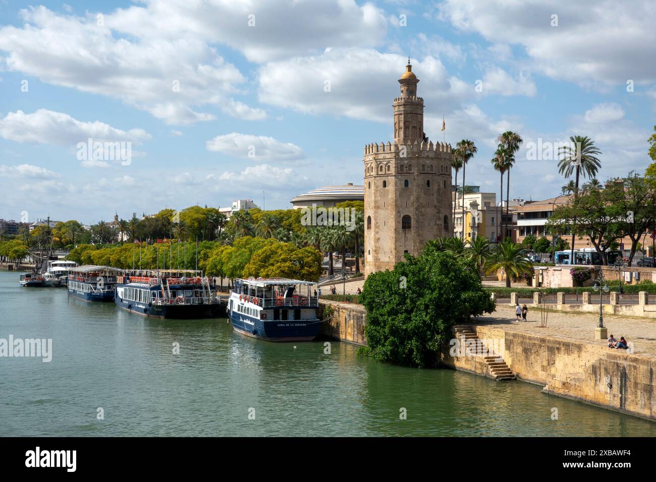 Sevilla, Andalusien, Spanien - 10. Juni 2024: Touristenboote liegen neben dem Torre del Oro (Goldturm) am Guadalquivir-Fluss vor. Stockfoto