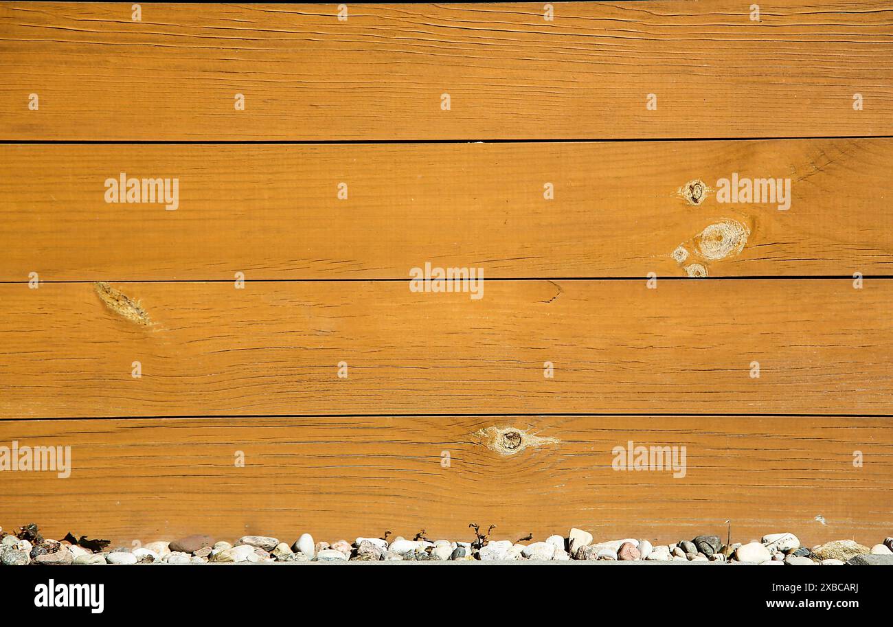 Nahaufnahme horizontaler Holzdielen mit rustikaler Textur über einer Reihe kleiner Steine, Hintergrundbild Stockfoto