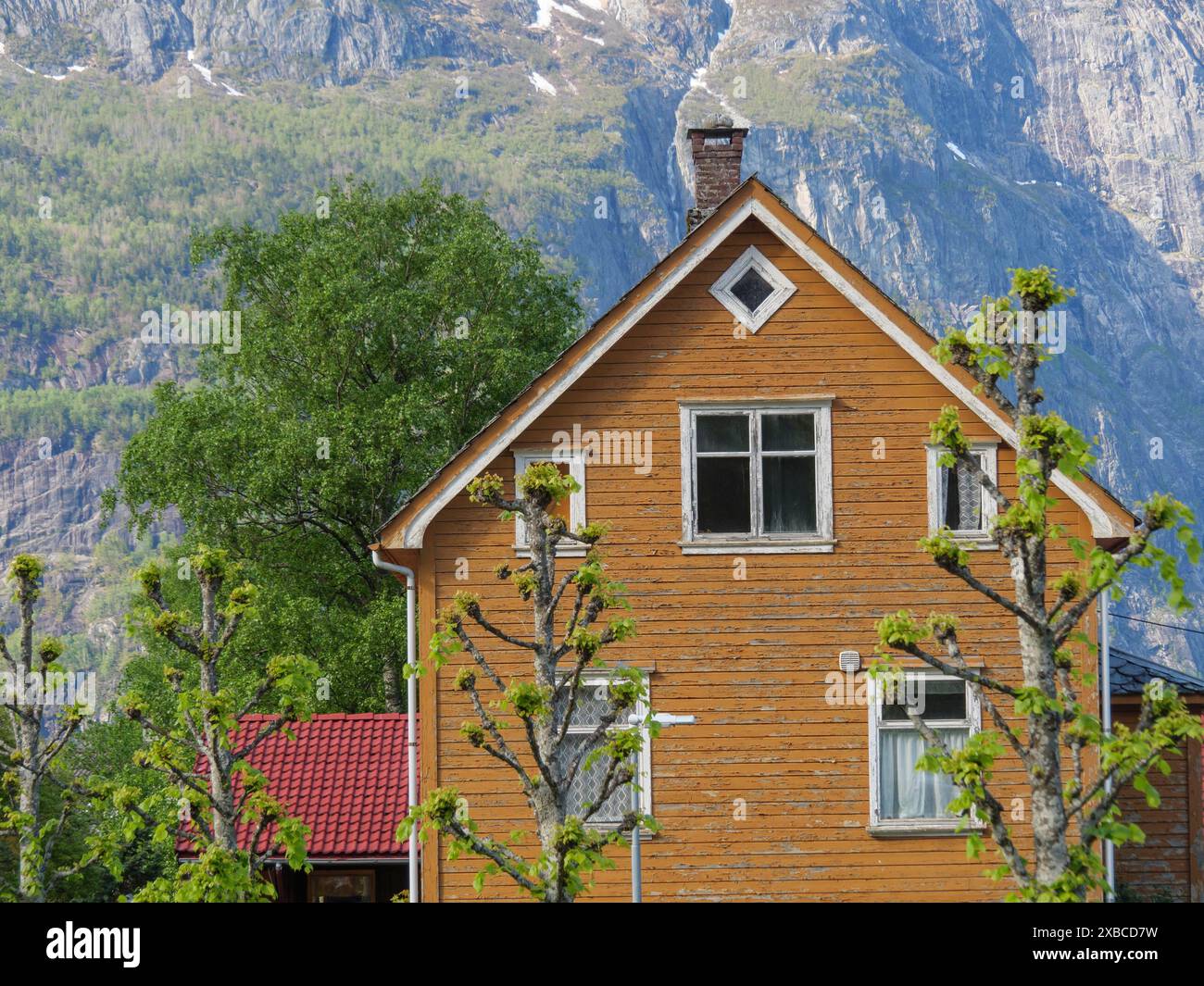 Einzigartiges Holzhaus in ländlicher Umgebung, umgeben von grünen Bäumen und hohen Bergen, Eidfjoerd, Norwegen, Skandinavien Stockfoto