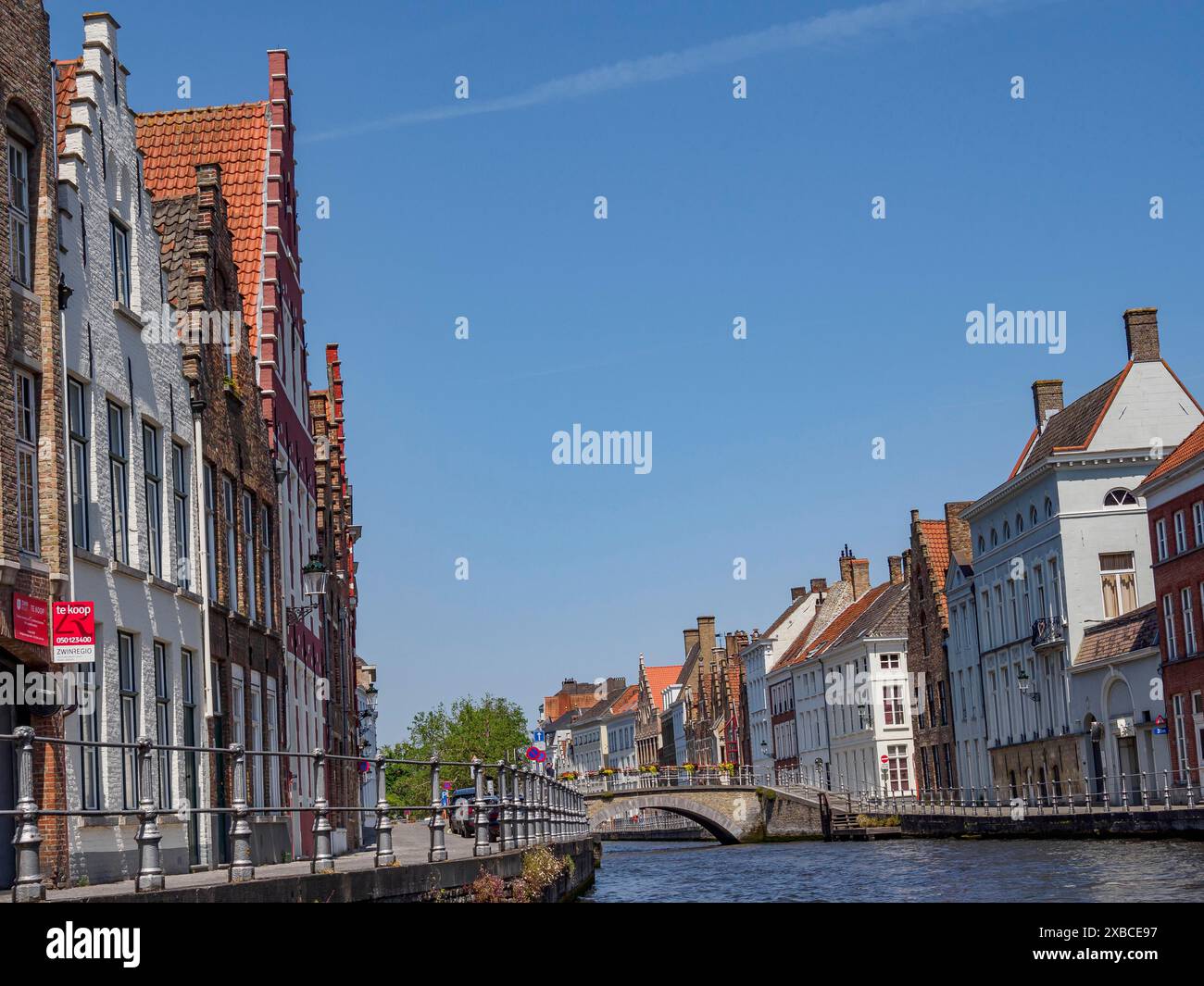 Flussufer mit historischen Gebäuden und Menschen, die entlang des Kanals laufen, Brügge, Flandern, Belgien Stockfoto