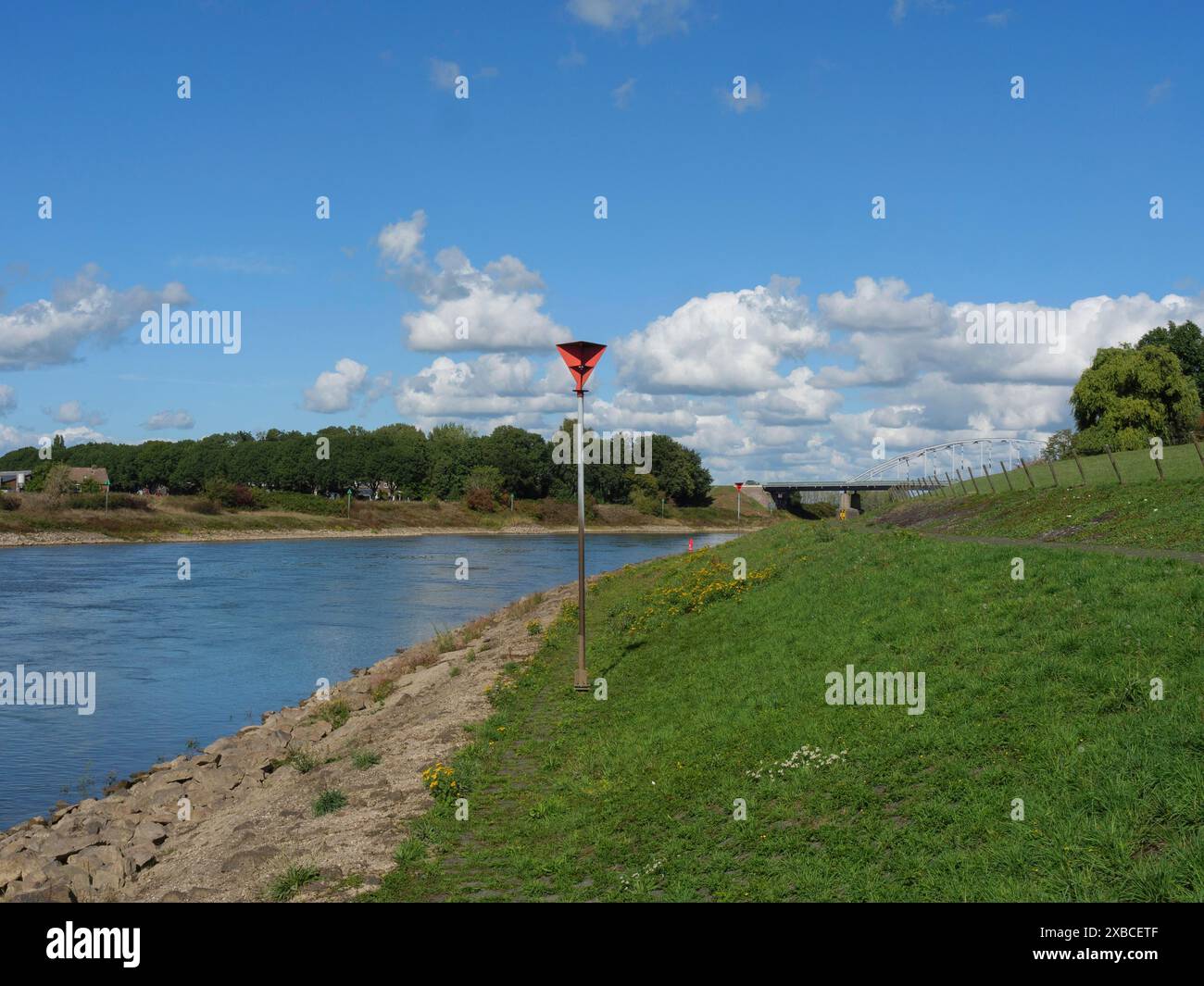 Flussufer mit Pfosten unter blauem Himmel, Doesburg, Gelderland, Niederlande Stockfoto