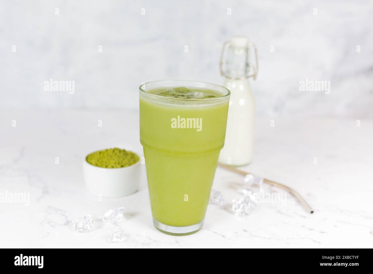 Japanischer Eismatcha Latte, grüner Tee mit Milch, Sojamilch mit Strohhalm im Glas vor hellem Hintergrund. Grüner Tee. Stockfoto