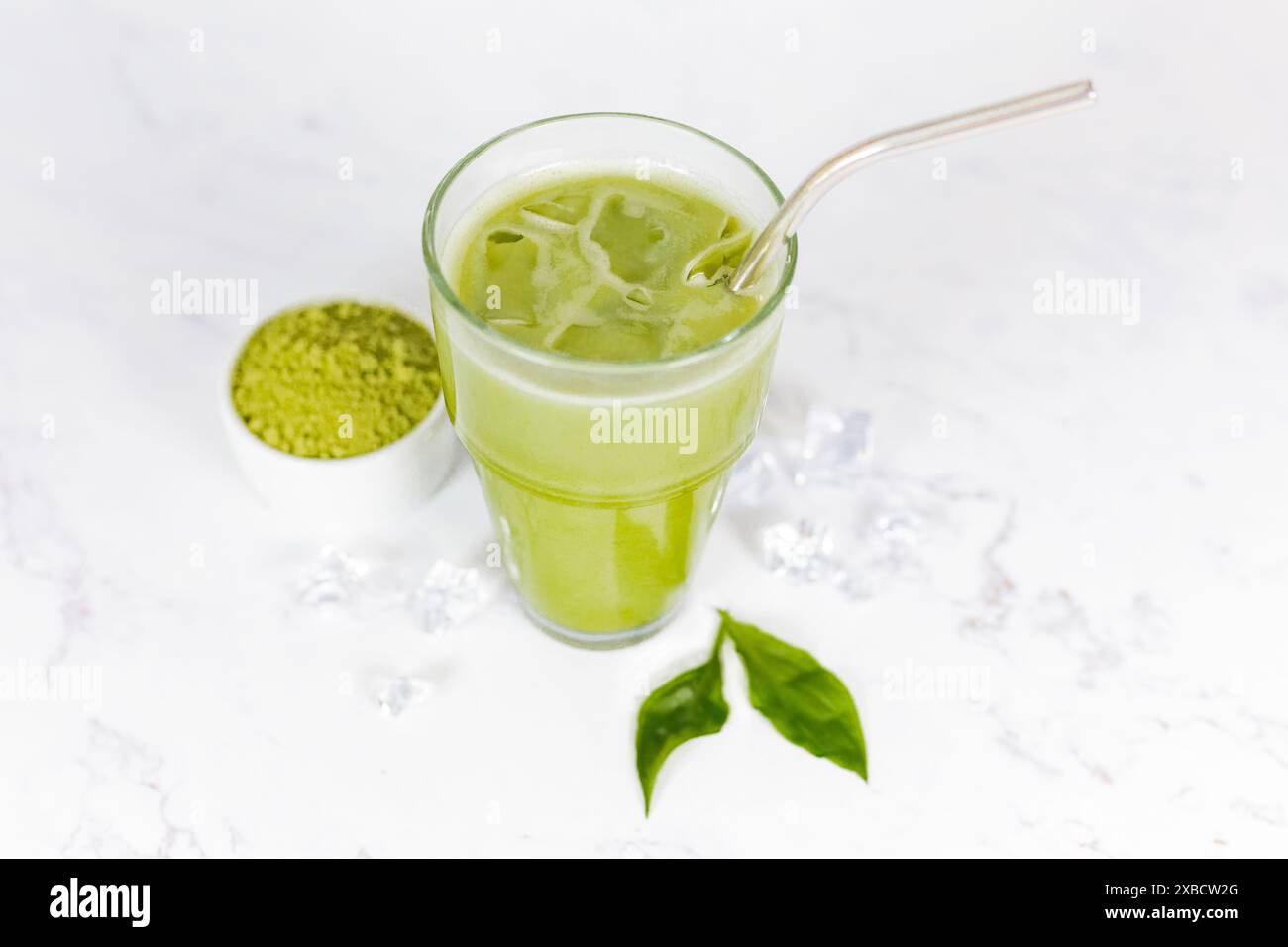 Japanischer Eismatcha Latte, grüner Tee mit Milch, Sojamilch mit Strohhalm im Glas vor hellem Hintergrund. Grüner Tee. Stockfoto