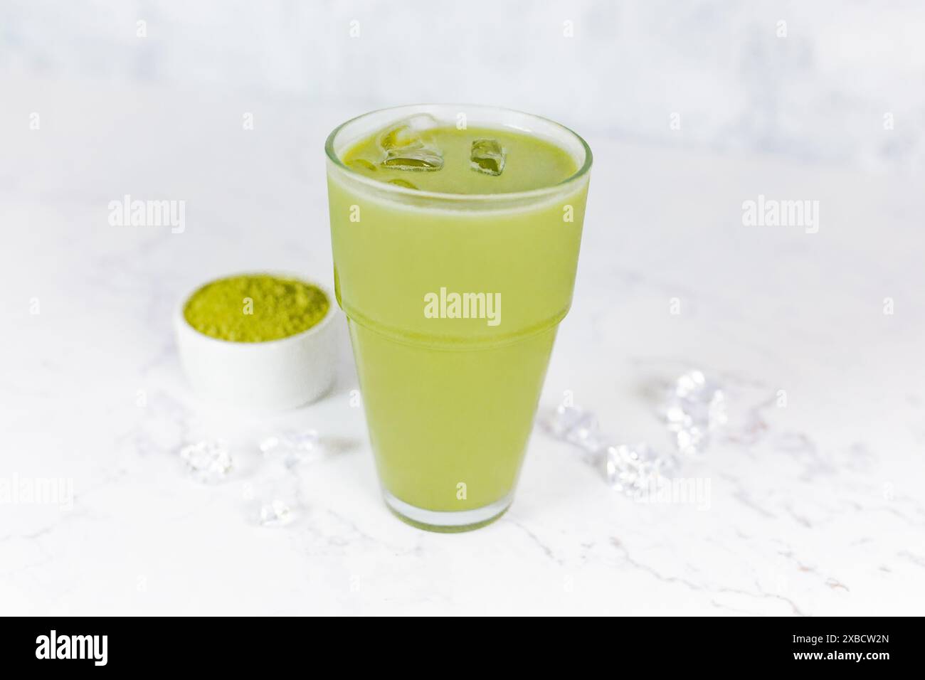 Japanischer Eismatcha Latte, grüner Tee mit Milch, Sojamilch mit Strohhalm im Glas vor hellem Hintergrund. Grüner Tee. Stockfoto