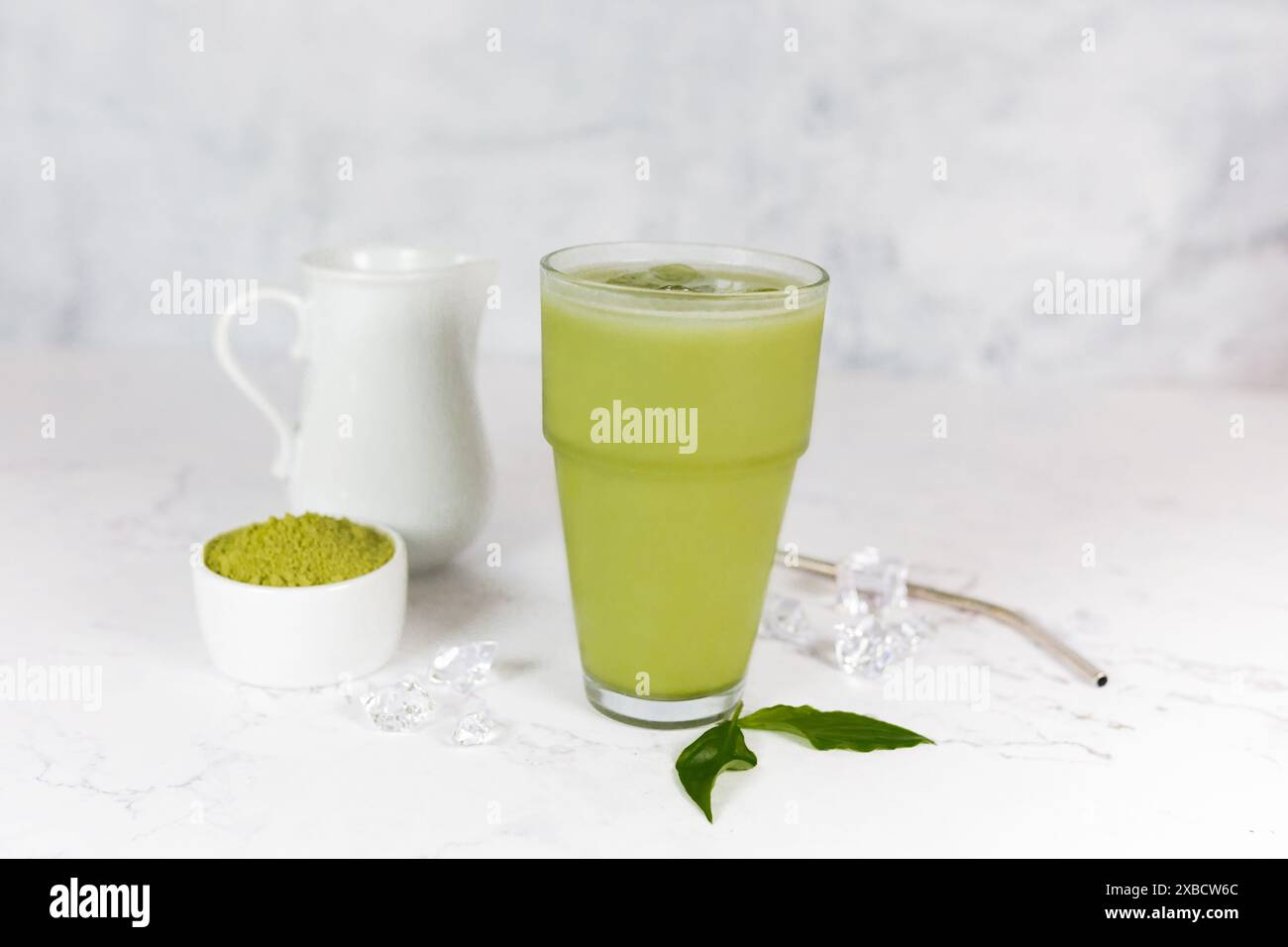Japanischer Eismatcha Latte, grüner Tee mit Milch, Sojamilch mit Strohhalm im Glas vor hellem Hintergrund. Grüner Tee. Stockfoto