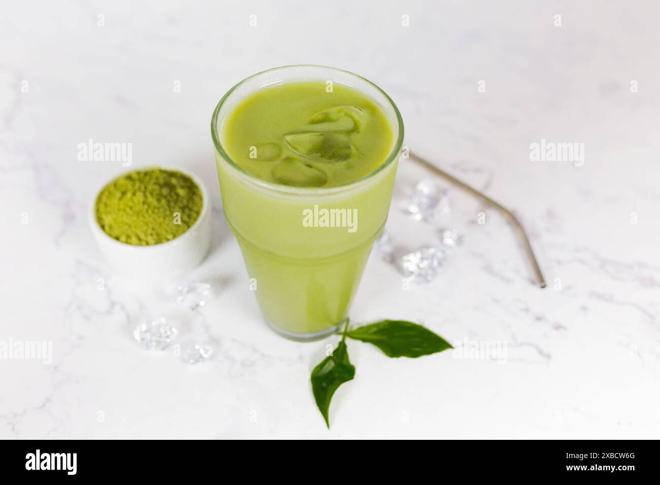 Japanischer Eismatcha Latte, grüner Tee mit Milch, Sojamilch mit Strohhalm im Glas vor hellem Hintergrund. Grüner Tee. Stockfoto