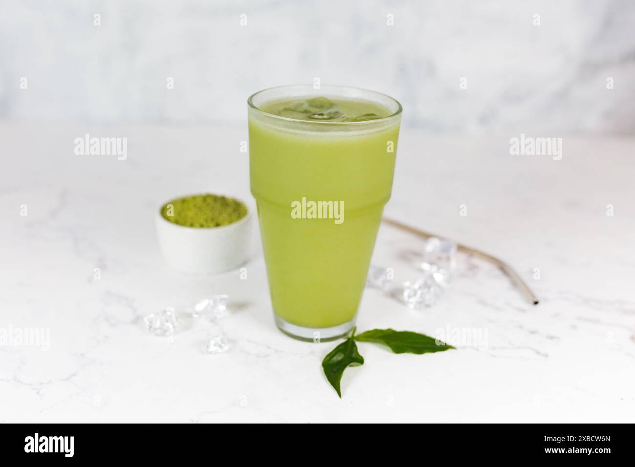 Japanischer Eismatcha Latte, grüner Tee mit Milch, Sojamilch mit Strohhalm im Glas vor hellem Hintergrund. Grüner Tee. Stockfoto