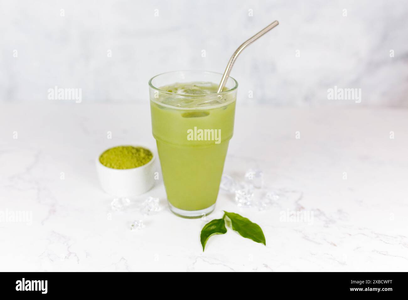 Japanischer Eismatcha Latte, grüner Tee mit Milch, Sojamilch mit Strohhalm im Glas vor hellem Hintergrund. Grüner Tee. Stockfoto