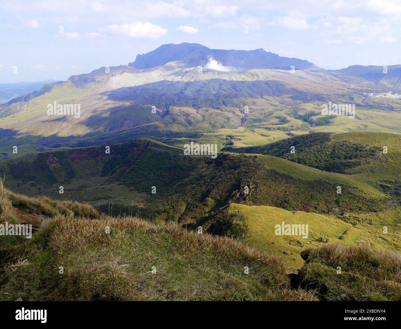 Landschaft auf der Spitze des Kishima Dake in der Aso Caldera, mit Blick auf den aktiven Vulkan mit Fumarole. Grüne Graslandschaft und ferne Vulkane in Kyushu, japan Stockfoto