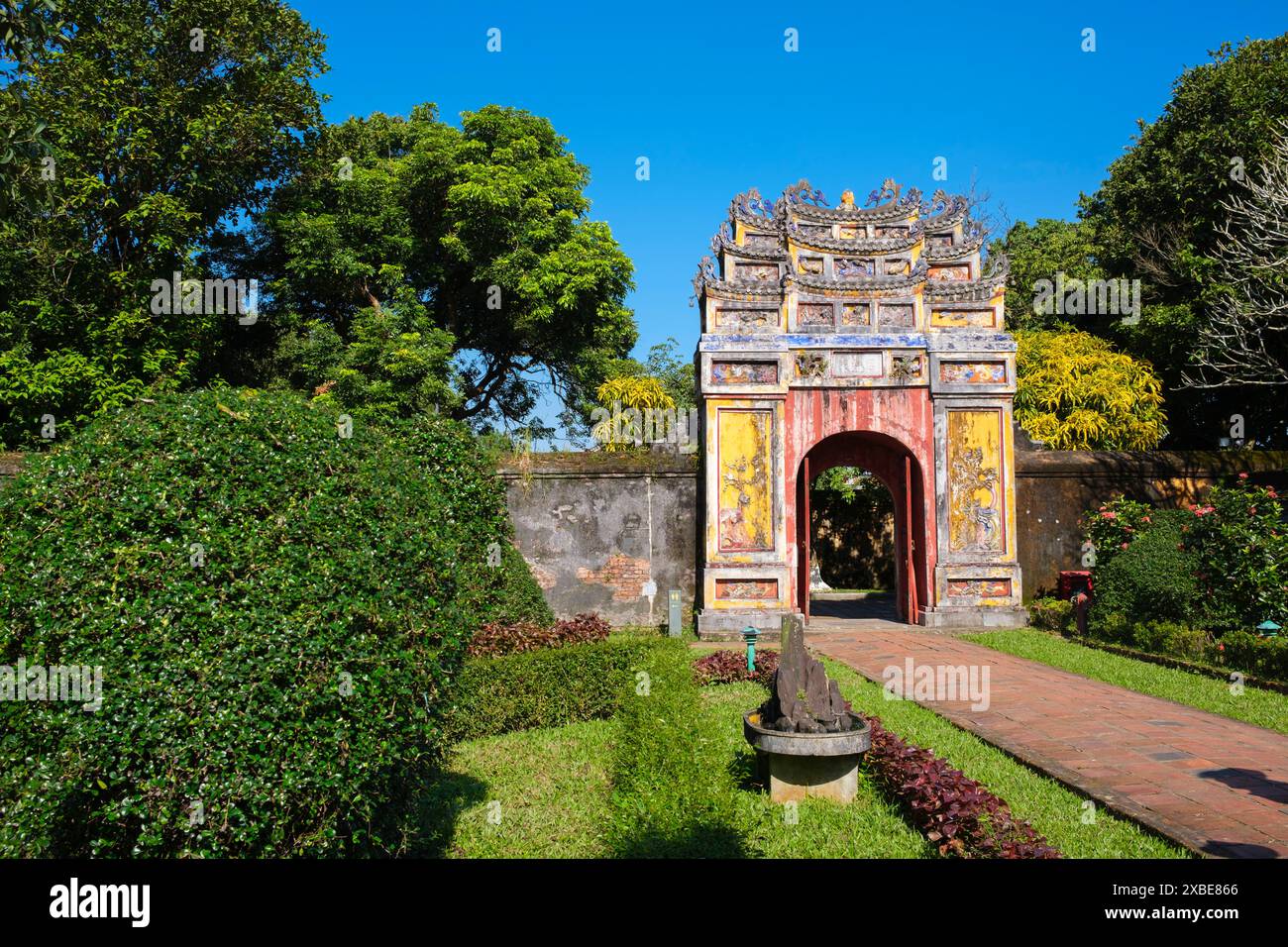 Vietnam: Ein Tor, das aus dem Thế Miếu (dem Mieu)-Tempel führt, die Kaiserstadt, die Zitadelle, Hue. Der Thế Miếu ist ein Ahnentempel, der 1822–23 auf Befehl von Kaiser Minh Mạng errichtet wurde. Er ehrt die Kaiser der Nguyễn-Dynastie. Kaiser Gia Long ordnete 1805 den Bau der Zitadelle von Hue an. Der weitläufige Komplex wurde nach den Vorstellungen des Fengshui oder der chinesischen Geomanz errichtet, aber nach den militärischen Prinzipien des bekannten französischen Militärarchitekten Sebastien de Vauban aus dem 18. Jahrhundert. Stockfoto